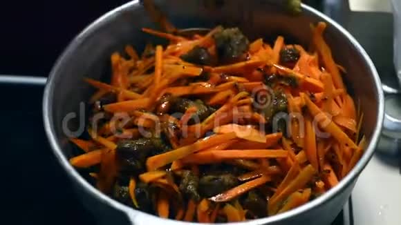 厨师把肉和胡萝卜混合在肉汤里在铸铁大锅特写中烹饪厨师把切好的胡萝卜加到视频的预览图