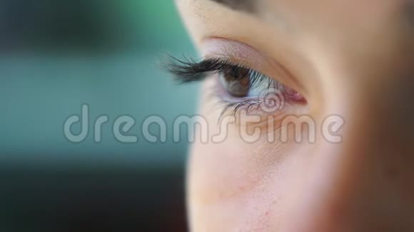 年轻女子淡褐色的眼睛在模糊的背景特写上眨眼视频的预览图