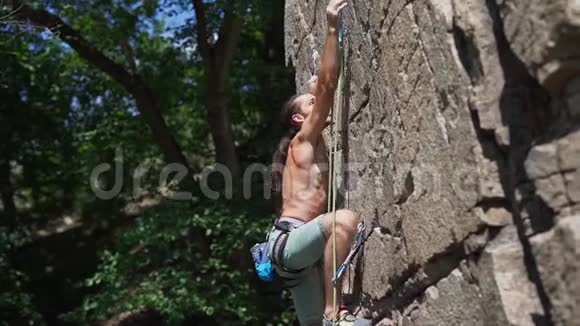 年轻的肌肉男攀岩者在艰难的运动路线上攀爬寻找到达和抓住视频的预览图