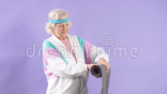 快乐的女性退休老人手里拿着瑜伽垫来到工作室上瑜伽课视频的预览图