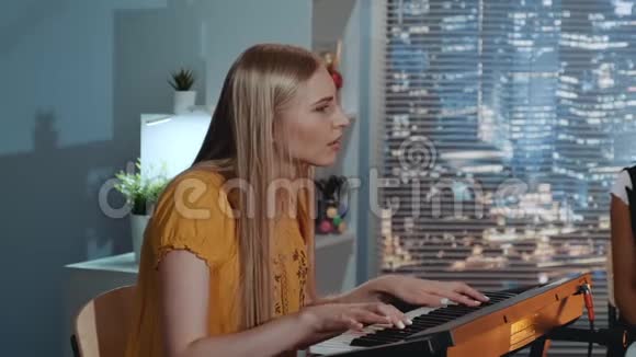 歌手金发碧眼的歌手在家录音室的乐队排练时唱着一首歌弹奏着键盘视频的预览图