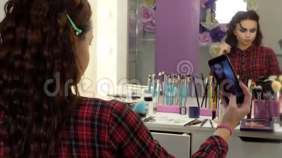 万圣节化妆很简单美容院的女孩在智能手机上拍照视频的预览图