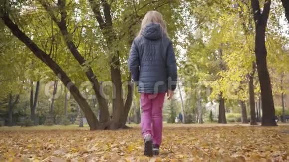 一个白人少女在秋天公园散步回头看镜头可爱的少年视频的预览图