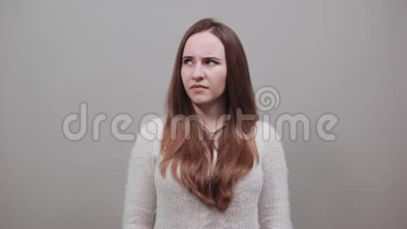 困惑的女人用毛衣把自己打得的手指放在脸颊上视频的预览图