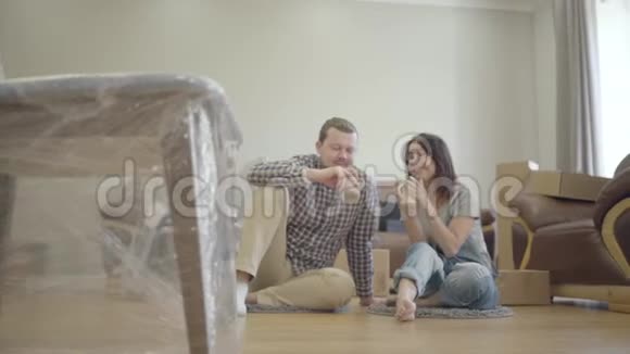 年轻的高加索家庭坐在地板上客厅里有新的家具和谈话一对幸福的夫妇视频的预览图