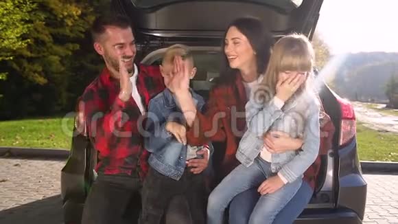 幸福的微笑漂亮的家庭坐在后备箱里互相击掌视频的预览图