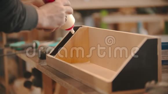 木工工作工人用胶水涂在木头上的手用胶合板制作木制组织者视频的预览图