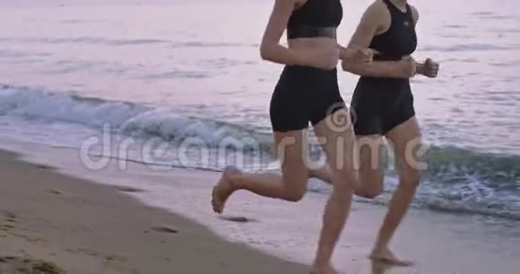 早上两位女士穿着运动服在海滩上的特写跑步腿4k视频的预览图