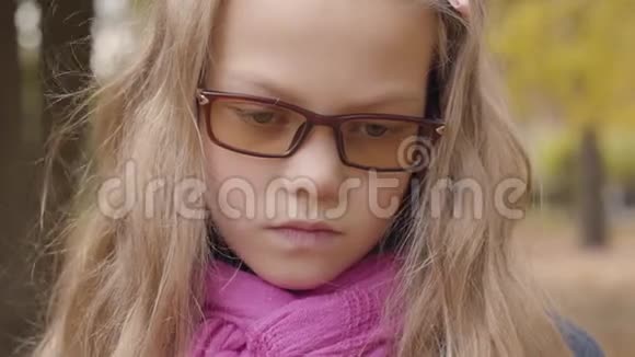 一个悲伤的高加索少女站在秋天公园里看着镜头的特写肖像青年视频的预览图