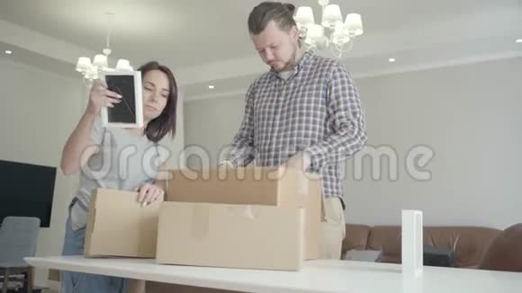 幸福的年轻夫妇在新房子里收拾行李积极的白人家庭站在客厅里视频的预览图