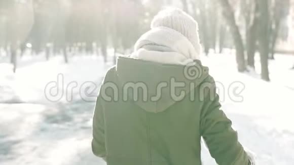慢镜头后景的女人穿着温暖的冬衣走在白雪皑皑的冬季城市公园里阳光明媚视频的预览图