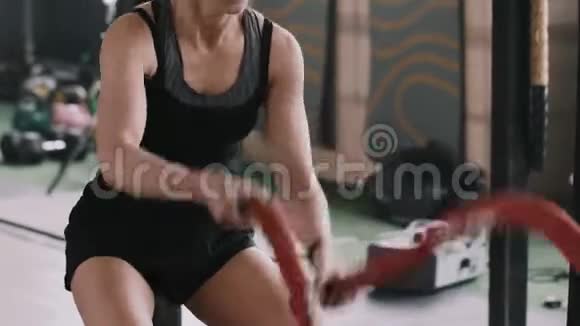 年轻漂亮专注运动的金发女人用战绳锻炼身体专注于大型健身房的训练视频的预览图