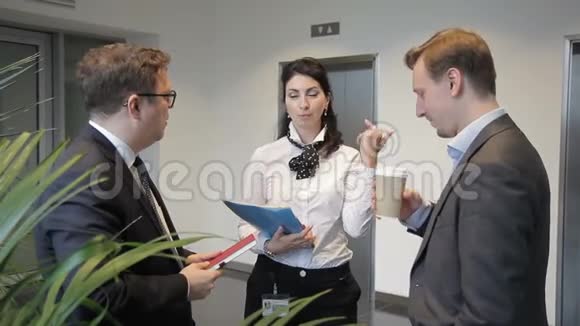 两个男人和女人正在交谈笑着站在公司的大厅里视频的预览图