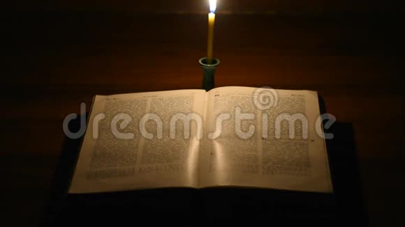一支孤独的蜡烛在黑暗的房间里燃烧在一本开放的书面前视频的预览图