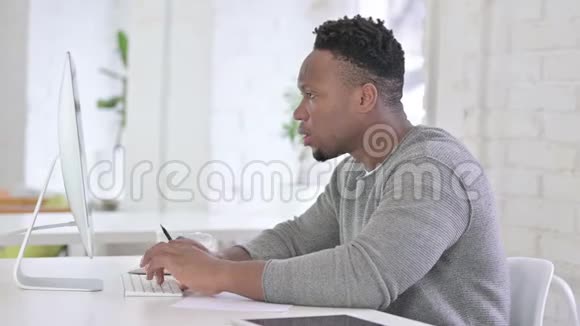 专业非洲青年男子办公室桌面研究视频的预览图