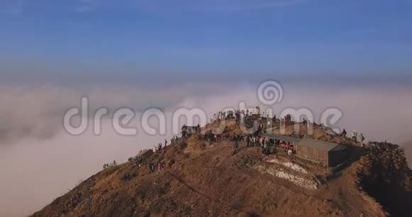日出时巨大的巴厘岛火山峰被云层包围上面有一群游客镜头飞起来审判视频的预览图
