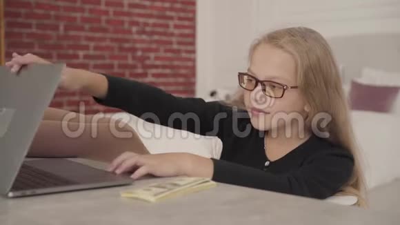 一个快乐的白种人少女的特写镜头推开笔记本电脑挥霍金钱有自信的女学生视频的预览图
