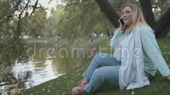 坐在湖岸公园背景的女士加号视频的预览图