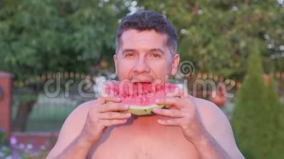 英俊的中年人在户外吃一个多汁的西瓜视频的预览图
