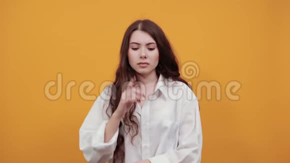 不快乐的迷人的深褐色头发的年轻女人手指贴在脸颊上视频的预览图