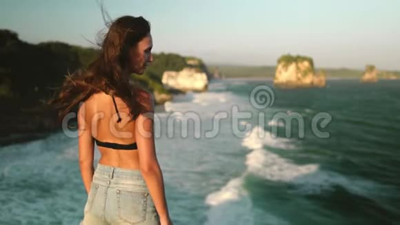 站在悬崖边有风的巴纳瓦海滩的女人视频的预览图