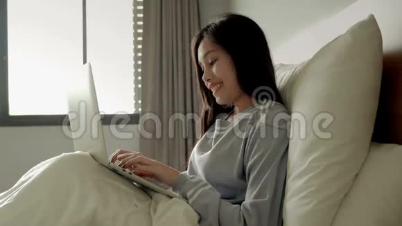 漂亮的女孩在床上用笔记本玩社交网络视频的预览图