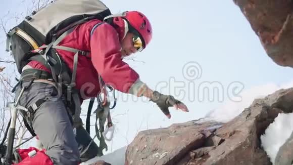 一个穿着红色西装和装备的登山者跪着靠在冰斧上爬山视频的预览图