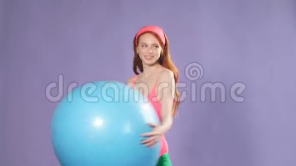 运动可爱的生姜女孩做运动与蓝色健身球使热身锻炼视频的预览图