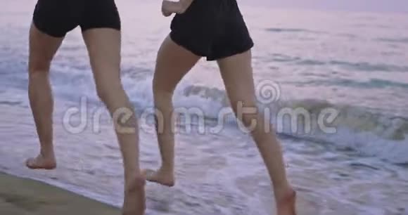 两位穿着运动服的漂亮女士一起在海滩边跑步听无线音乐视频的预览图