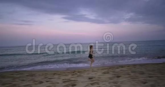 一位美丽的年轻女士早上穿着运动服在海滩边跑步的大视频慢慢慢慢视频的预览图