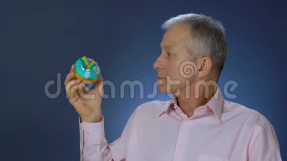 一个身材苗条的白发男人穿着衬衫看着蛋糕拒绝吃选择吃一个绿色的苹果视频的预览图