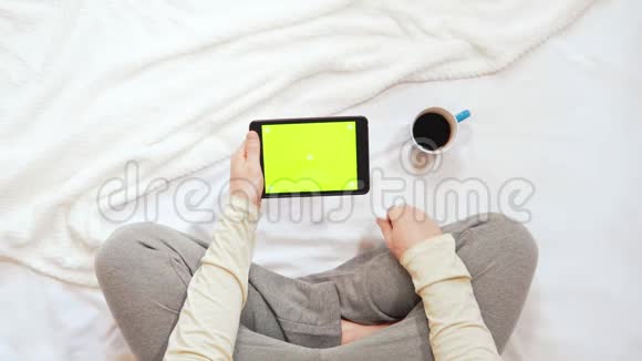 顶景男子坐在床上使用带有绿色屏幕的设备视频的预览图