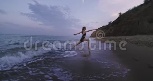令人惊叹的海滩景观年轻穿着运动服练习瑜伽冥想姿势同时站在水面上缓慢的动作视频的预览图