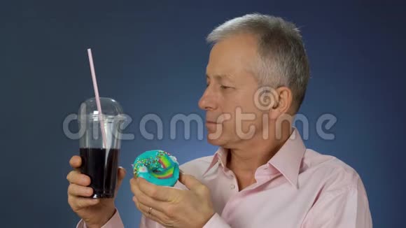 一位身材苗条的中年男子正拿着一杯汽水和一个蛋糕提议用视频的预览图