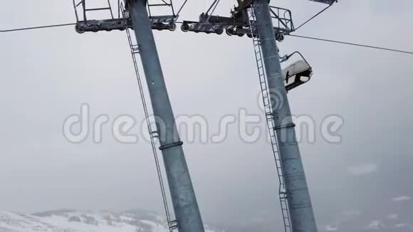 在阴天的冬季在山顶移动滑雪椅升降台视频的预览图