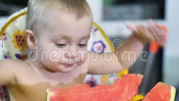 漂亮的小男孩在厨房的孩子们的桌子上吃西瓜然后微笑着快乐地笑了进来视频的预览图