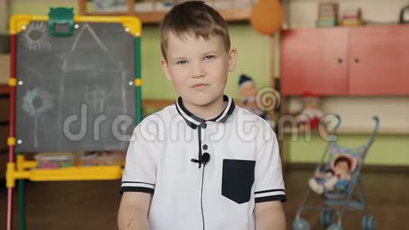 一个穿白色衬衫的男孩坐在相机前的椅子上衣服上有麦克风回答问题视频的预览图