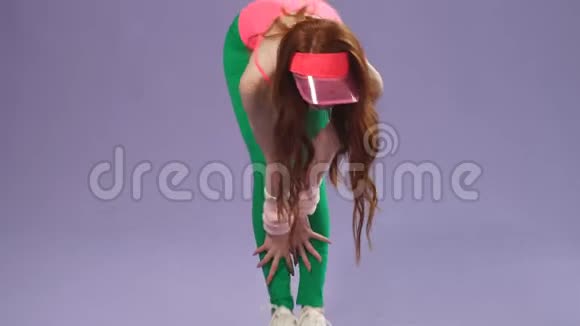 穿着80年代风格的粉色紧身衣和绿色紧身裤的红发女孩视频的预览图