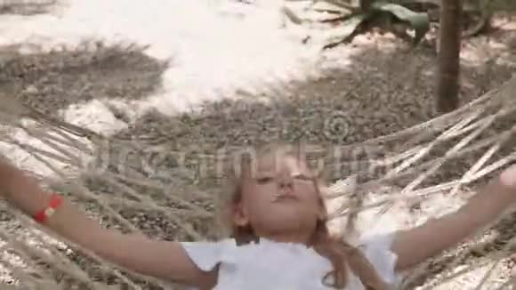 夏日里躺在吊床上放松的女孩暑假期间快乐的女孩在吊床上休息视频的预览图