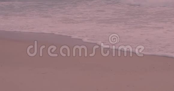 夕阳红沙滩上带泡沫的海浪视频的预览图