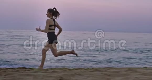 职业跑步女士在早晨海滩边集中跑步穿着黑色运动服视频的预览图