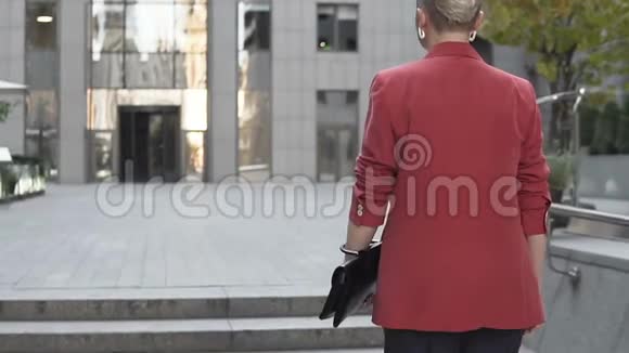 金发短发女人穿着红色夹克走在街上视频的预览图