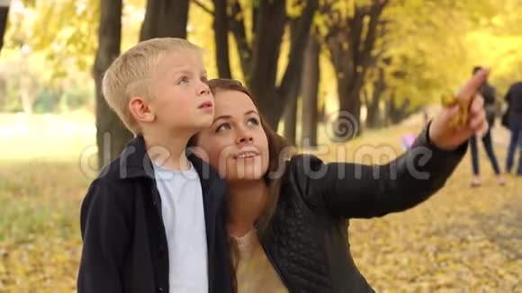 美丽的母亲和两个儿子在秋天的公园里散步视频的预览图