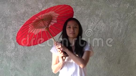 用传统的红伞微笑东南亚女子肖像慢动作视频的预览图