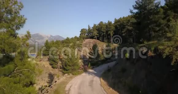 附近有森林的壮丽山路晴天鸟瞰4k视频的预览图