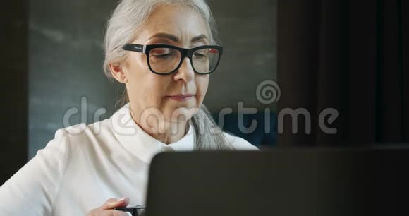 有笔记本电脑和咖啡的老年妇女视频的预览图