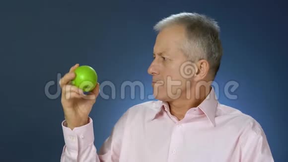 一个穿衬衫的中年男子在苹果和蛋糕之间做出选择并通过抛出一个苹果来选择蛋糕视频的预览图