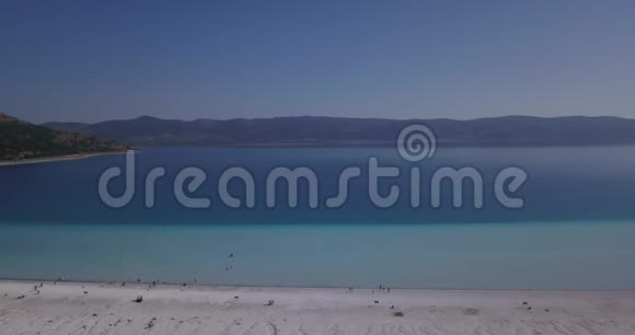 巨大的萨尔达湖带着蓝色的水人们在海滩上散步和游泳视频的预览图