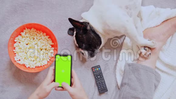 男人在室内拿着智能手机吃爆米花视频的预览图