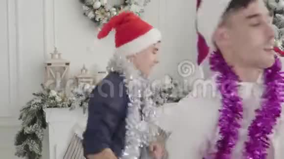 快乐的白种人朋友在装饰好的圣诞树前跳舞快乐的孪生兄弟和她们的女人一起玩视频的预览图